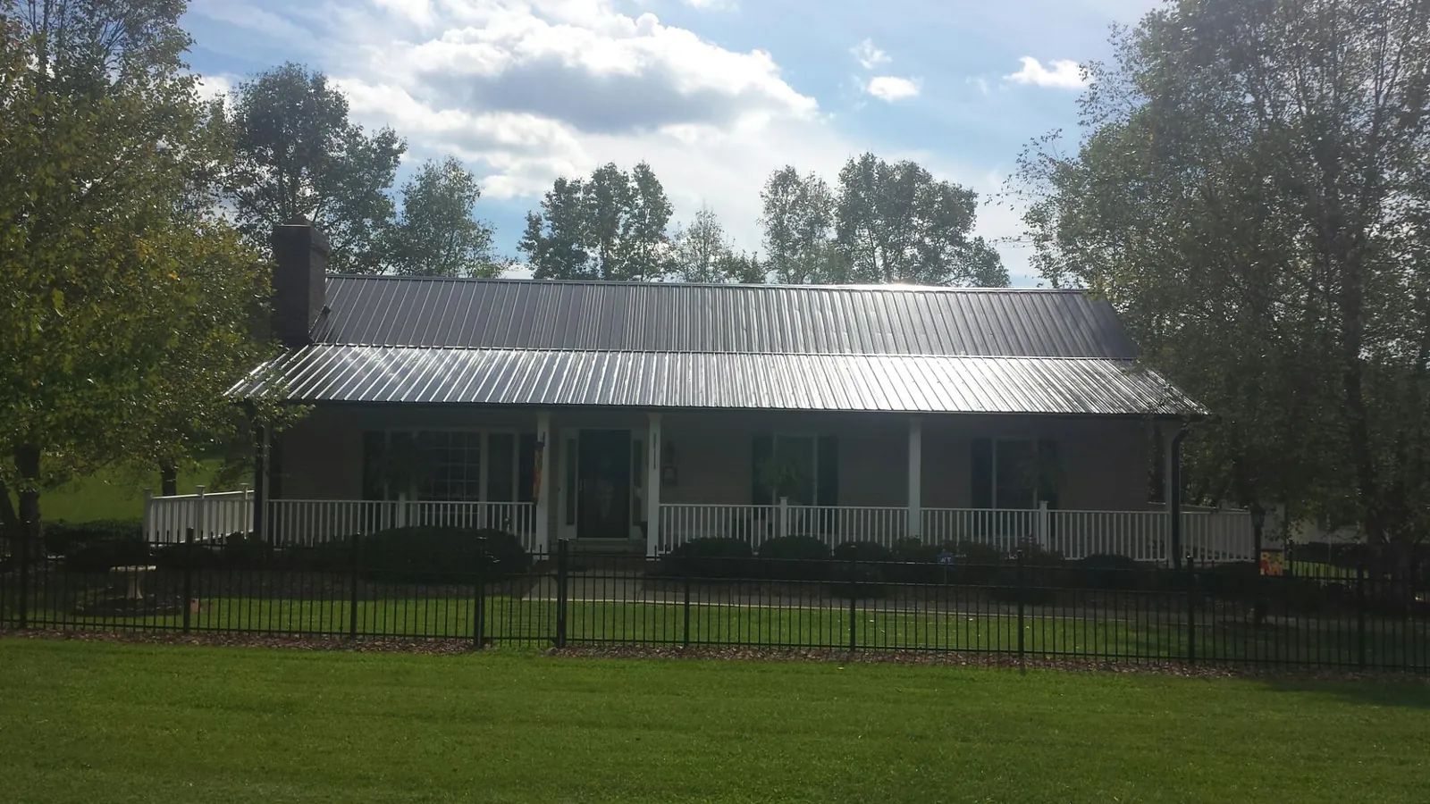 Gray metal roof on a brick ranch with a full width front porch — Gutter Guard Installation work by our crew in Stewartsville